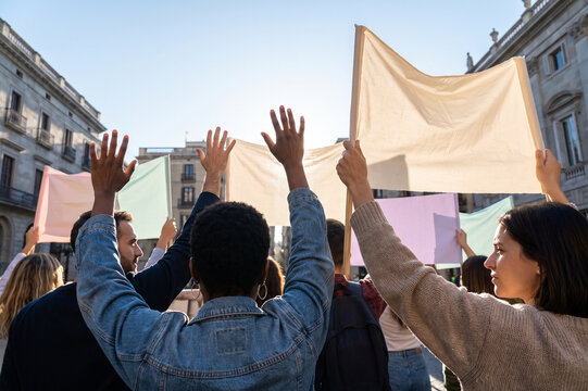 Protesters raising blank signs and hands in an urban square during daylight demonstrating solidarity and civic engagement for campaigns and community events