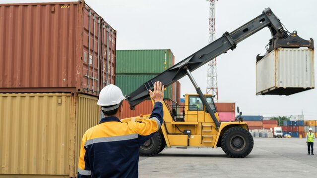 Worker directing reach stacker in shipping yard