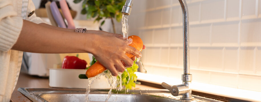 Person washing fresh vegetable under running water in bright kitchen sink, supporting healthy food preparation and daily household hygiene with natural light and clean surroundings
