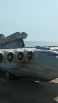 Footage of an abandoned Soviet-era ekranoplan ground effect aircraft resting on a sandy Caspian Sea shoreline near Derbent, Dagestan, Russia, in daylight