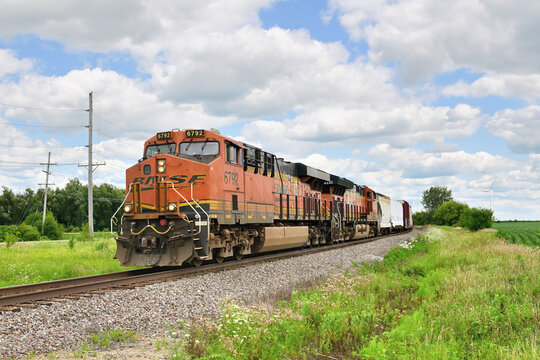 Multiple locomotives lead a westbound Burlington Northern Santa Fe grain train around a curve while passing through agriculturally dominated north central Illinois.