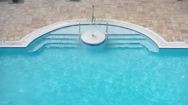 Top view of swimming pool steps with clear blue water. Summer vacation, poolside relaxation, and spa retreat.