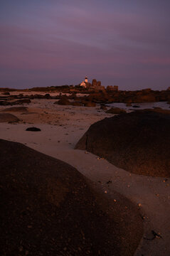 The Pontusval lighthouse, located on a rocky point in northern Finistere in Brittany at early sunrise . Vertical banner, travel, tourism