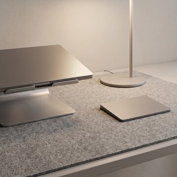 Minimalist aluminum laptop stand on grey felt desk pad, modern silver trackpad workstation setup, clean aesthetic home office desk accessories