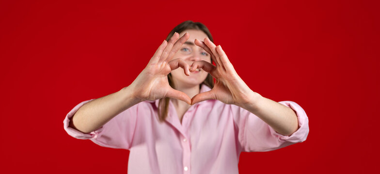 Studion shot of happy woman showing heart with her hands. St Valentines copy space banner 