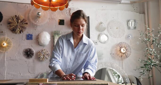 Focused young woman handmade craft professional preparing wide glass sheet for fabrication process marking layout lines to define cutting positions developing production template in glasswork studio