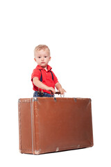 Child stands on a suitcase with hands on top while looking at the camera in a studio setting during daytime © Nikola Spasenoski
