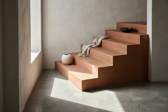 Minimalist Terracotta Staircase Interior Design with Natural Sunlight and Decorative Ceramic Vases in a Modern Architectural Setting
