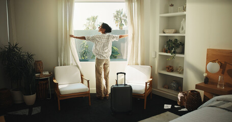 Fototapeta premium Window, curtain and happy woman with suitcase in hotel for holiday getaway, travel or vacation. Back, mature person and relax with sunshine for weekend or morning stay in luxury bedroom or resort