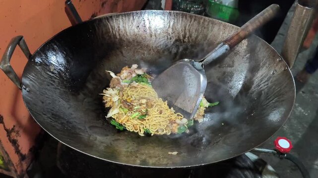 Indonesian fried noodles, or mie goreng, prepared by a street food vendor with yellow noodles, vegetables, seasonings, and savory toppings, representing a popular and flavorful Indonesian street food 