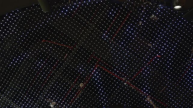Abstract illuminated ceiling grid with thousands of sparkling LED lights and red structural elements in a modern interior