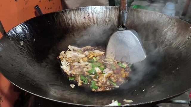Indonesian fried noodles, or mie goreng, prepared by a street food vendor with yellow noodles, vegetables, seasonings, and savory toppings, representing a popular and flavorful Indonesian street food 