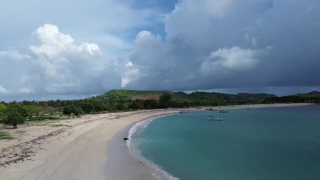 High-angle drone footage of the scenic Batu Berang Beach coastline in Lombok, West Nusa Tenggara (NTB), Indonesia, featuring crystal clear ocean waves and nature.
