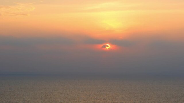 A nature sky panoramic scenic view of a vibrant sunset or sunrise sky with glowing orange and yellow clouds transitioning into deep blue twilight, representing nature beauty, and tranquility at ocean