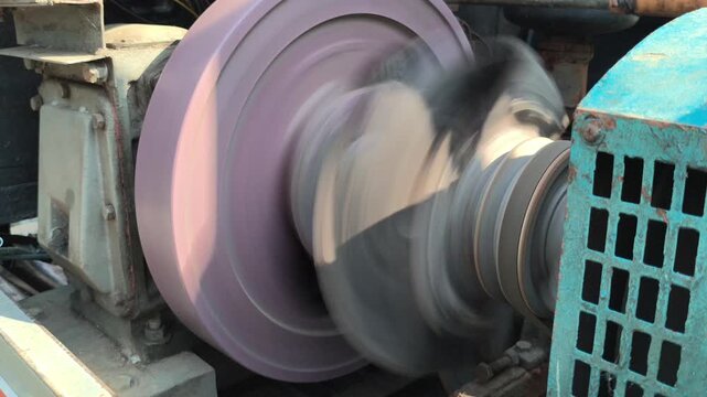 Close-up of a flywheel rotating on a diesel engine, showing the heavy metal wheel, mechanical components, and rotational motion that helps maintain smooth and continuous engine operation.