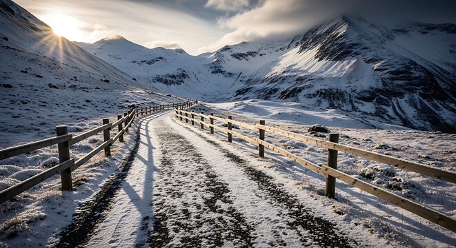Snowy mountain road with wooden fence winding through alpine landscape