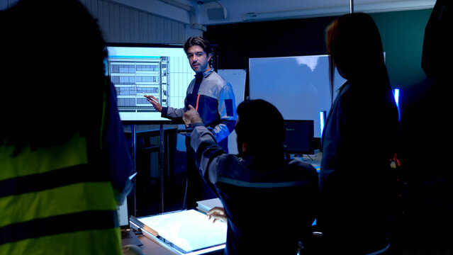 Multinational engineering and technology team collaborating in modern control room while analyzing software data