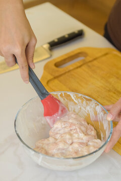 Close-up of a raw seasoned minced meat mixture being stirred in a bowl with a red spatula.