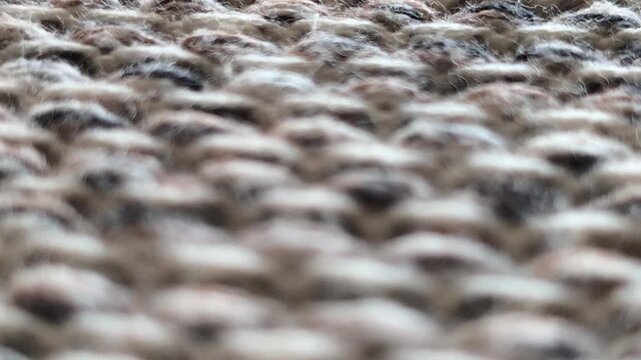 Close-up of a thick gray knitted or woven carpet surface featuring a dense pattern of tightly arranged yarn loops, creating a soft, textured appearance suitable for flooring, textile, and interior des