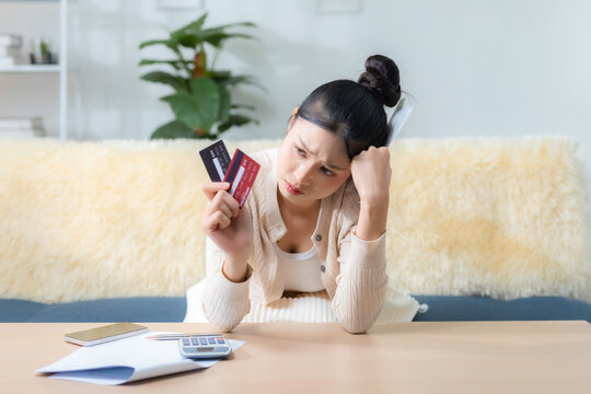 worried woman checks two credit cards with bills and calculator at home desk, personal finance, loan payment, budget stress, banking, debt, credit, bill. Credit card debt concept.