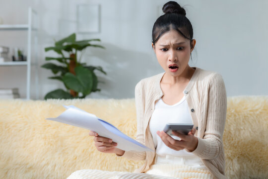 women looking shocked while checking bills, documents and calculator at home, representing financial stress, unexpected expenses, debt, budgeting problems, money management.