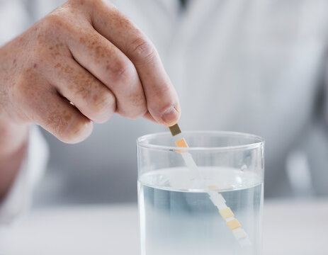 Hand testing water pH level with test strip