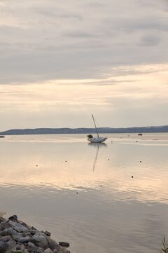 A peaceful sunset landscape at Lake Balaton in Hungary featuring a solitary sailboat resting on the ground due to low water levelsdrought, climate catastrophe.
