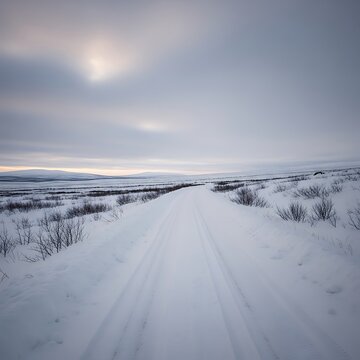 Snowy winding road stretching across frozen arctic tundra landscape under overcast sky