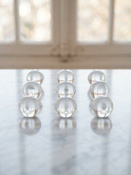 Nine clear glass spheres arranged in three rows on a reflective surface.