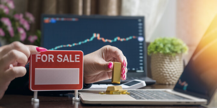 Selling physical gold bullion online. Female investor taking profit on the commodity stock market from a home office.