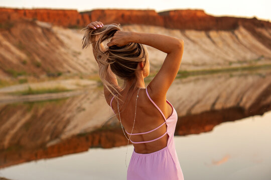 Blonde Woman Gathering Hair Against Rocky Quarry Landscape