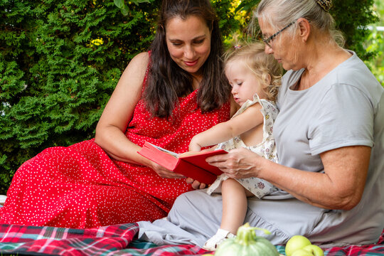 Three Generations Reading Together on Summer Garden Picnic