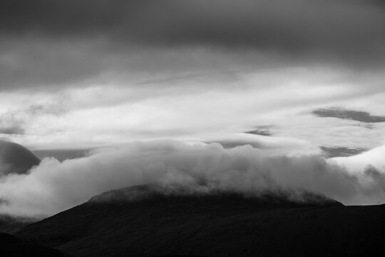 Monotone view of thick clouds rolling over mountain summits