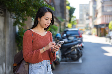 Obraz premium Woman typing on phone on street at Taipei city