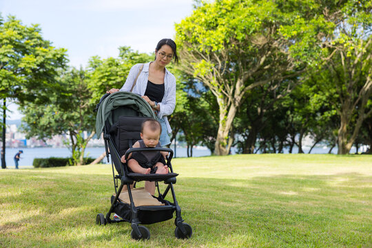 Mother pushing baby stroller in green park