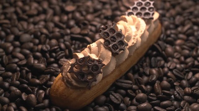 Gourmet coffee eclair with whipped cream and chocolate decoration resting on roasted coffee beans.