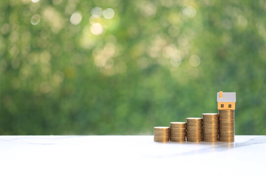 Mortgage,Model house and stack of coins money on natural green background,Business investment and real estate concept