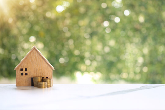 Wooden house model with stacks of coins on green bokeh background, Real estate investment, mortgage and property saving concept.
