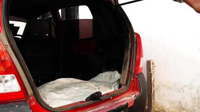 Person Closing Open Trunk Hatchback Rear Door of Red Car in Repair Garage