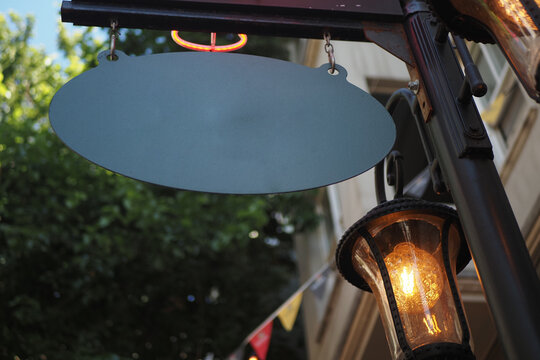 Sign hanging from a lamp post near trees and decorations in a city