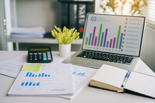 Business financial chart on laptop screen with desk documents and calculator for corporate accounting and data analysis