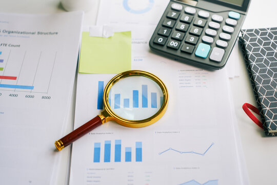 Financial data analysis with magnifying glass on business reports and calculator for accounting audit and corporate research strategy
