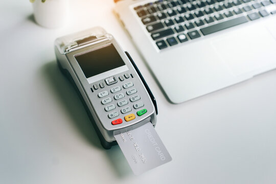 Credit card terminal for digital payment processing on office desk with laptop computer for ecommerce and fintech business financial transaction concept
