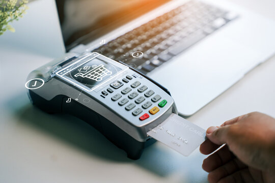 Contactless payment processing with credit card on portable point of sale terminal featuring digital shopping cart icon overlay for modern ecommerce financial technology
