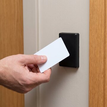 Hand presenting access card to wall-mounted door reader