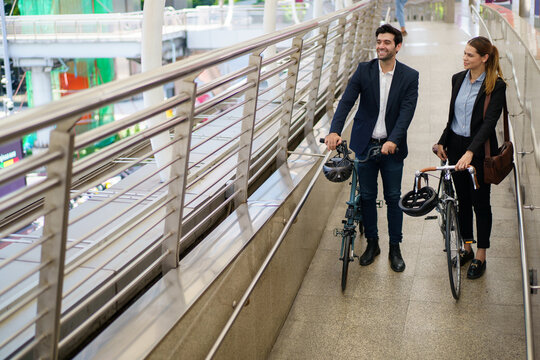 Caucasian business people walking with bicycle on city skywalk