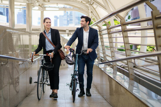 Business people pushing bicycles and talking on city skywalk bridge