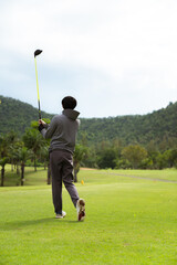 Fototapeta premium Golfer completing swing follow through with driver on green course
