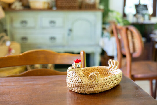 Woven straw basket on wooden table in warm rustic dining room creating charming handcrafted home interior scene with soft natural light and comfortable nostalgic atmosphere