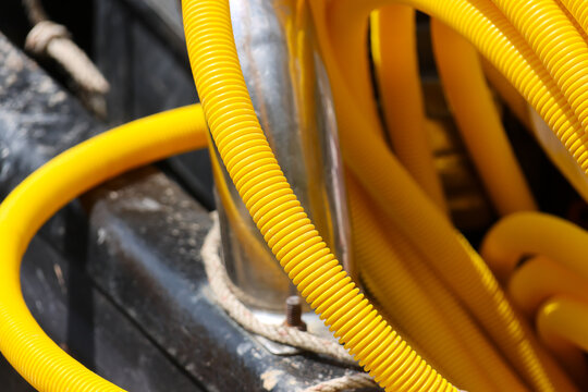 Yellow conduit corrugated tube metal pipe construction site industrial wiring flexible cable protective sleeve plastic tubing electrical installation utility connection yellow textured ribbed